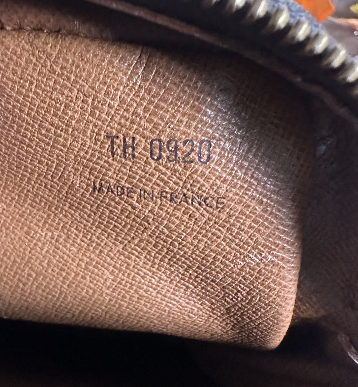 Close-up of the interior lining of a brown textured leather pouch or wallet, showing embossed text reading 'TH 0920' and 'MADE IN FRANCE'.